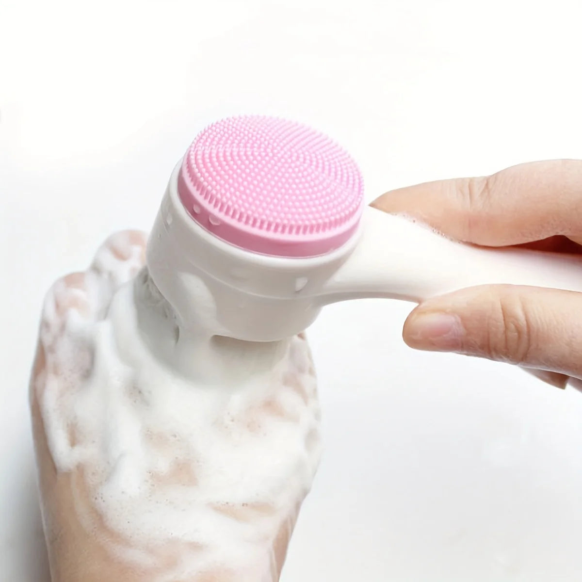 Eine Hand presst weiße Schaumsubstanz aus einem rosa Silikon-Paw-Cleaner mit zwei Seiten.