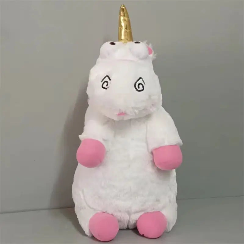 A white unicorn plush doll with a gold horn and pink accents sitting on a gray surface.