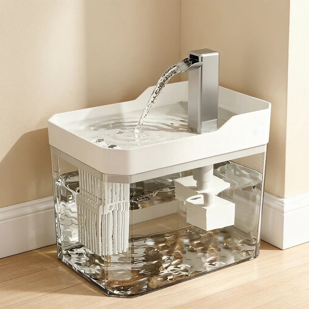 A clear cat water fountain with a white base and a stainless steel spout is shown on a wooden floor.