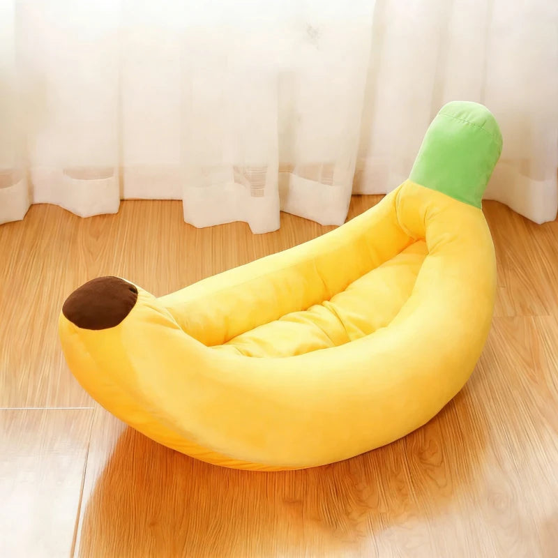 Un lit pour animal en forme de banane jaune avec une pointe verte, posé sur un plancher en bois.