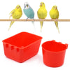 A bright red plastic bird feeder and water bowl with a square tray and a round bowl, shown next to several yellow and blue bi