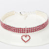 A silver collar adorned with pink and red rhinestones is displayed on a white plate.