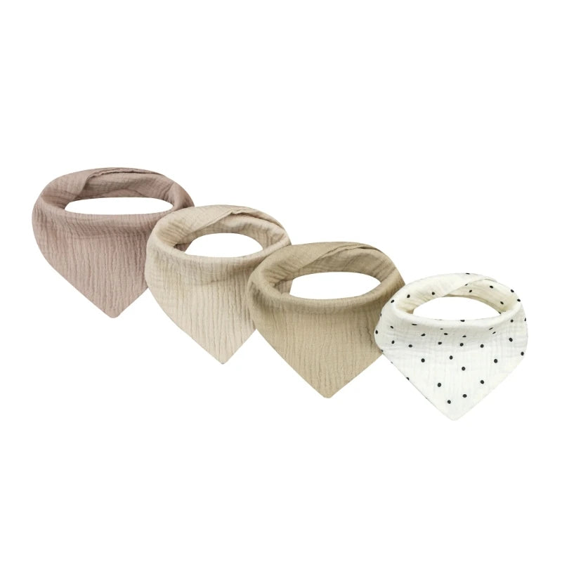 A set of four beige and white cotton baby bibs with various printed designs for newborns