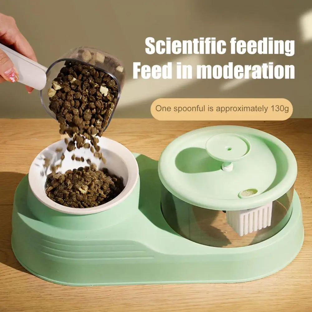 A hand is using a measuring scoop to feed pet food into a green plastic container on a wooden surface.