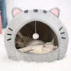 A gray plush cartoon cat cave bed with ears and facial markings, providing a cozy hideout for a small pet.