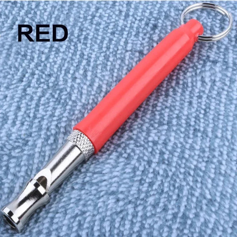 Red ultrasonic dog training whistle attached to a metal keyring on a blue fabric background.