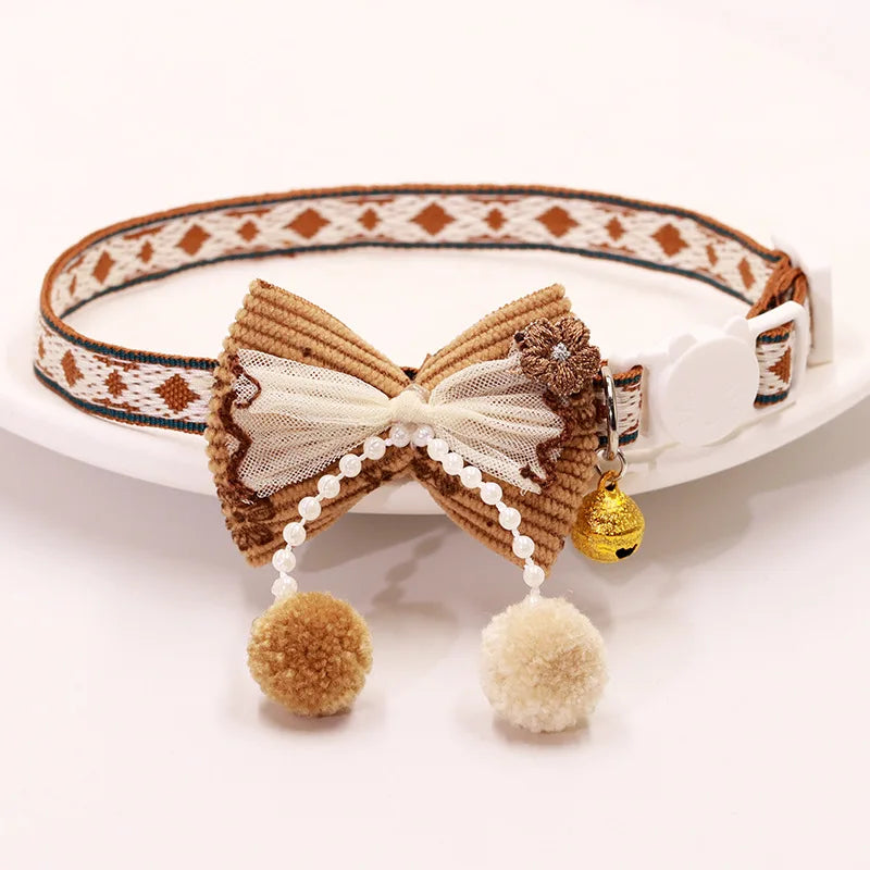 A brown patterned breakaway cat collar featuring a bowknot and a gold bell.