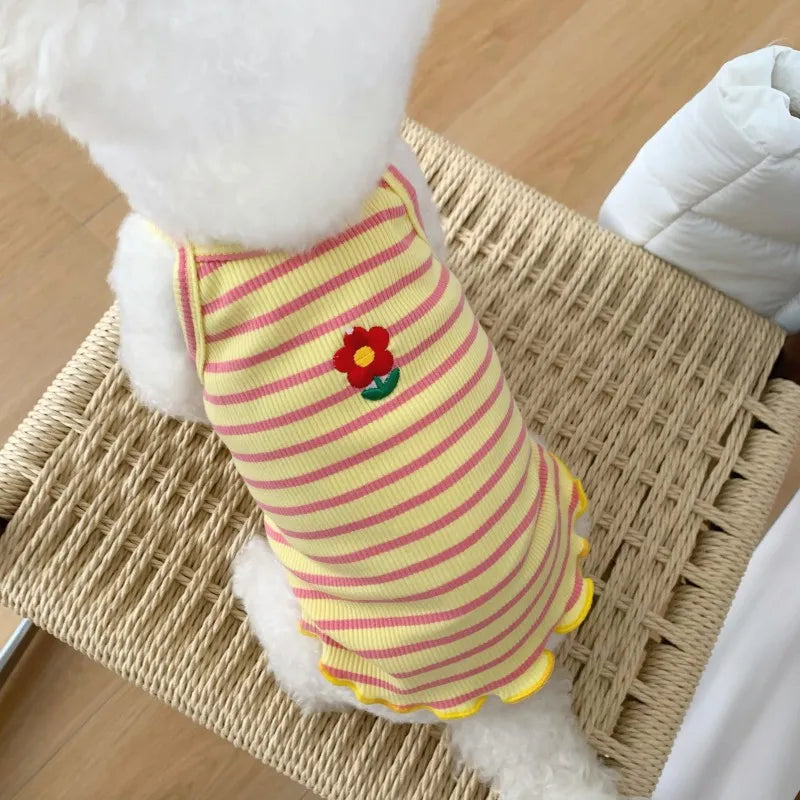 Ein gelb-rosa gestreiftes Kühlvest für Hunde liegt auf einer geflochtenen Matte.