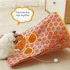 A white cat is playing inside an orange and teal crinkle fabric tunnel designed for hide and seek.