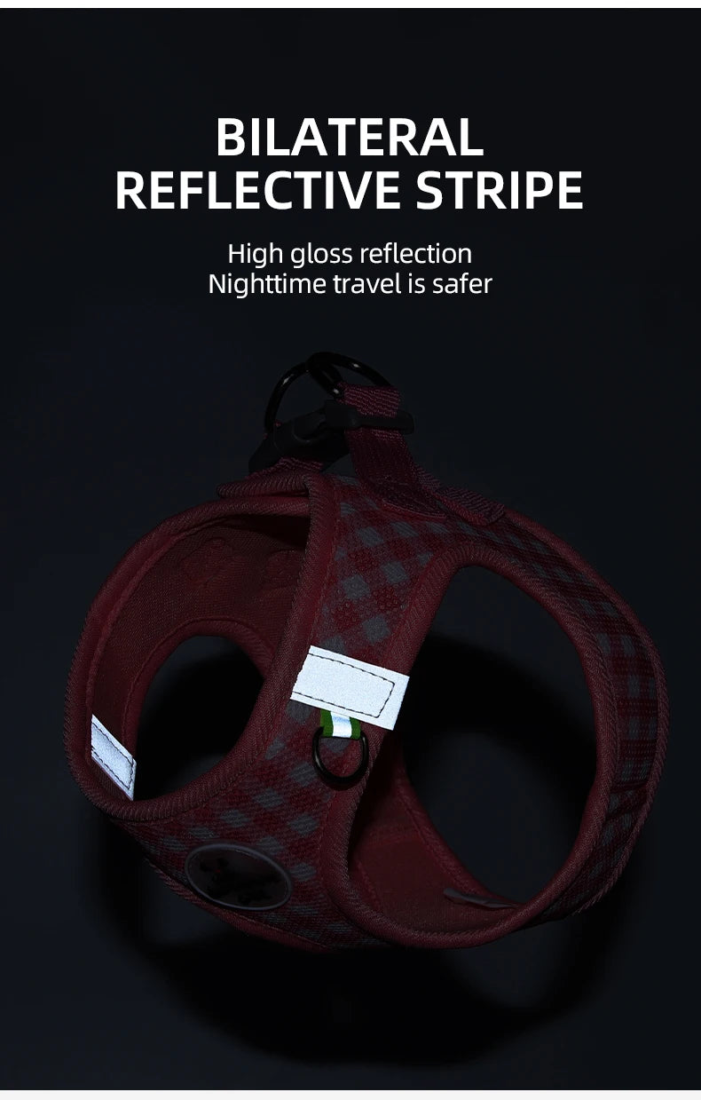 A maroon plaid pet harness with reflective stripes is shown against a dark background.