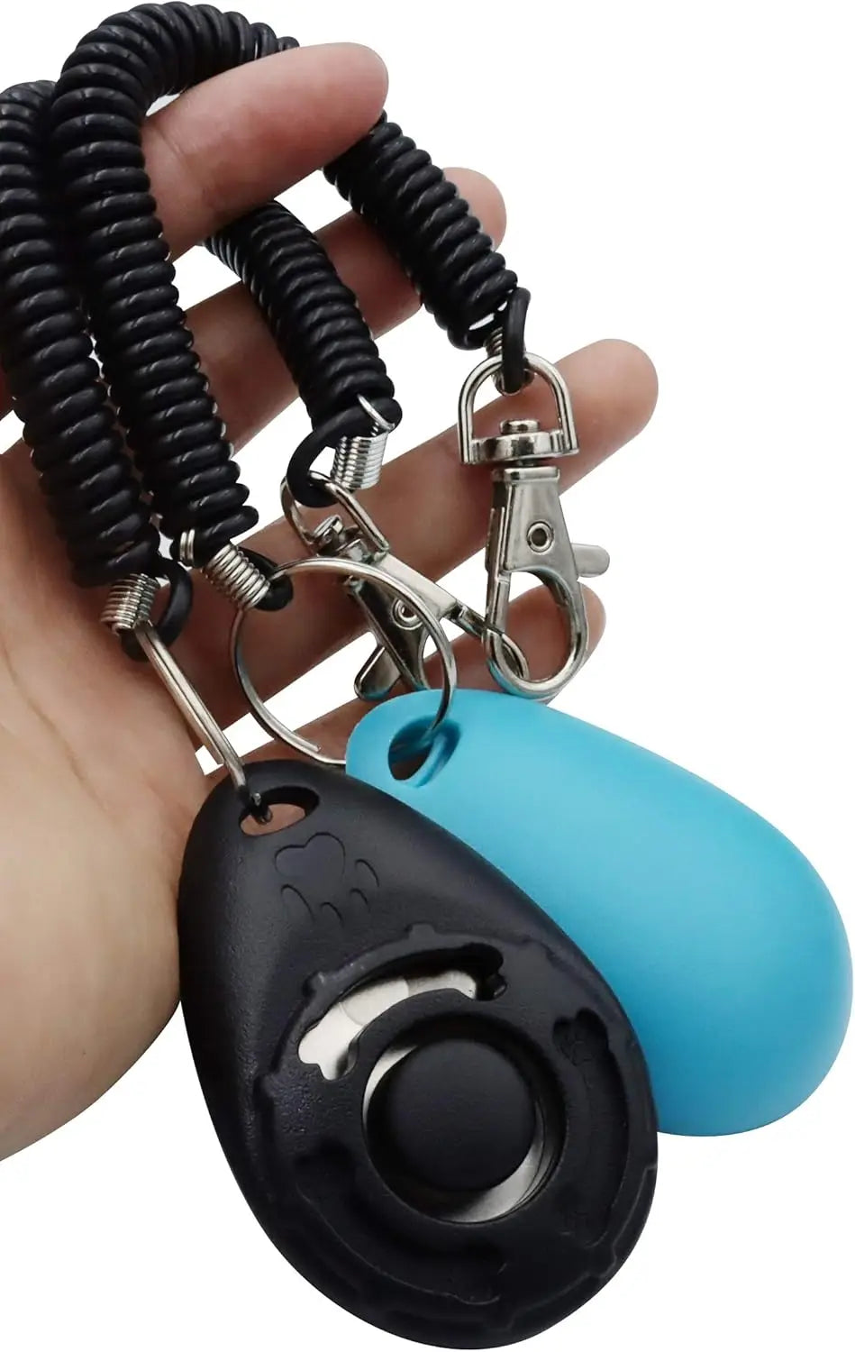A hand holds a black pet training clicker with a wrist strap attached, featuring a blue silicone body.