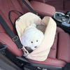 A white fluffy dog is resting inside a light pink portable soft-sided pet carrier placed in a car seat.