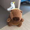 Brauner Capybara-Plüschtier mit einem weißen Flügel mit gelber Spitze.