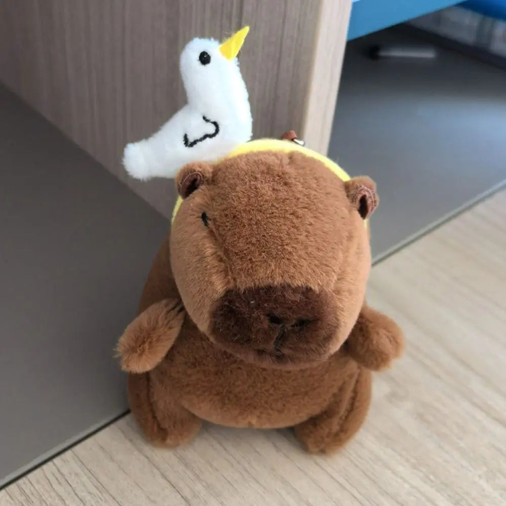 Brauner Capybara-Plüschtier mit einem weißen Flügel mit gelber Spitze.