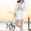 A woman holds an adjustable hands-free dog leash with a light blue handle and collar, standing outdoors.