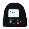 Black knitted beanie hat featuring a white cartoon face and colorful embroidered symbols on the cuff