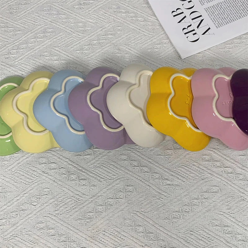 A row of decorative ceramic flower-shaped pet bowls and dipping dishes in rainbow plum blossom colors.