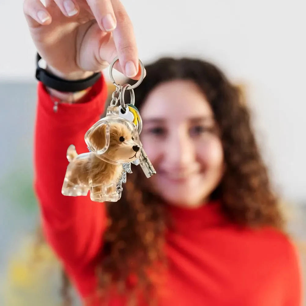 A woman holds up a clear dog hair keepsake pendant on a keychain against a white background.