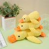 A yellow crocheted plush duck toy for dogs with orange feet resting on a green surface.