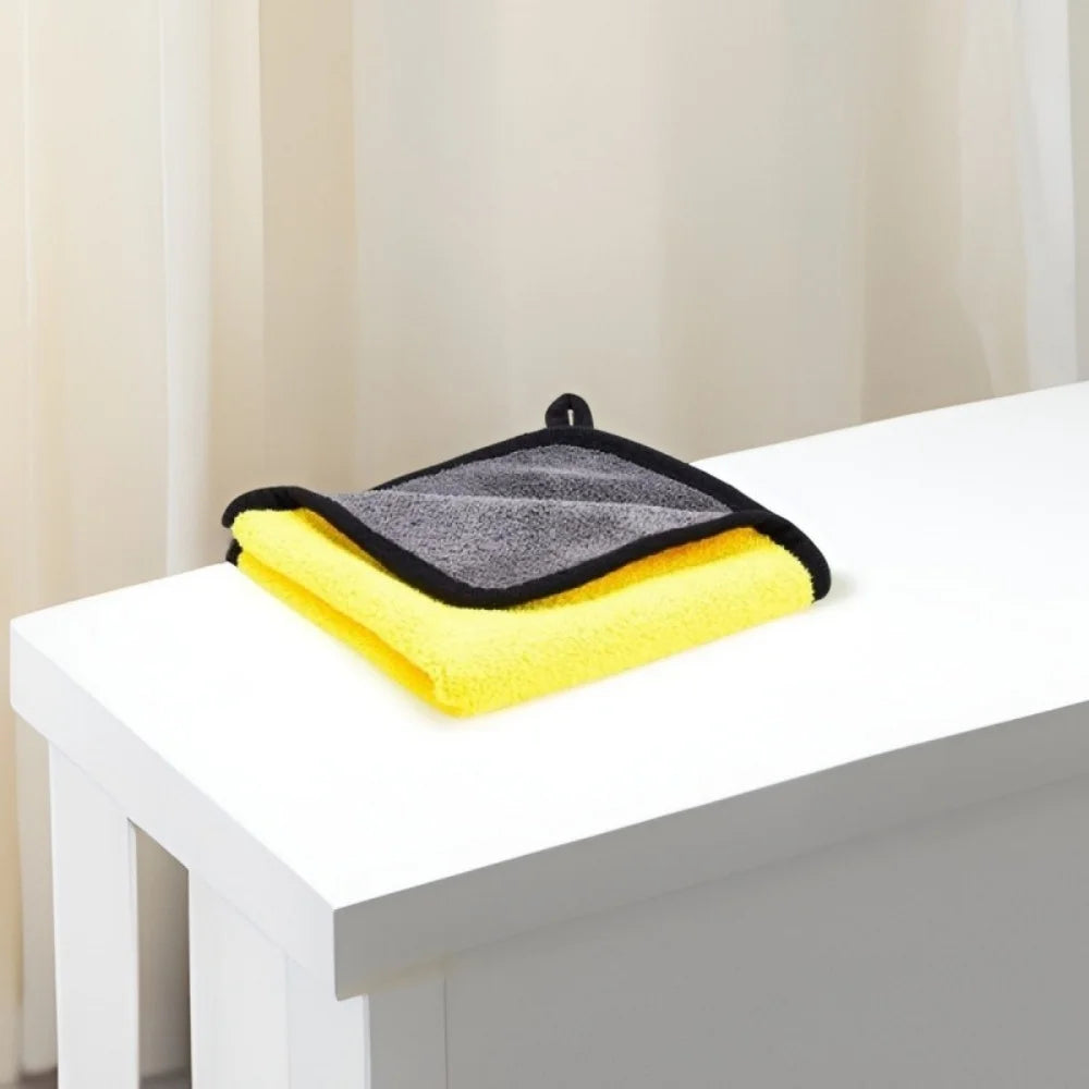 A stack of yellow and gray ultra-absorbent pet drying towels resting on a white table.