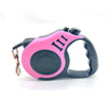 A pink and black automatic retractable dog leash with a black handle is shown against a white background.