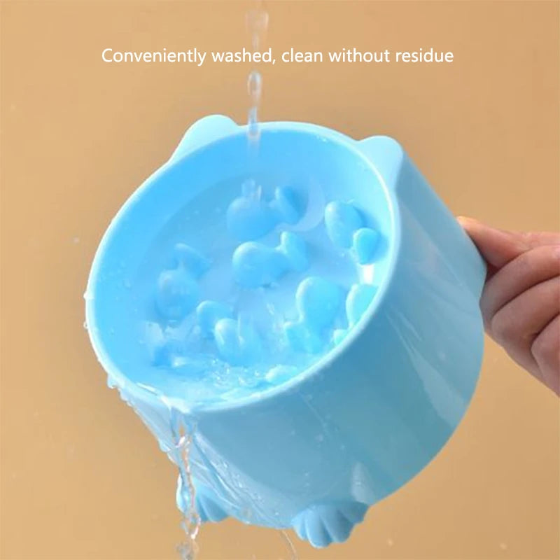 A light blue anti-choking slow feeder bowl being washed under running water.
