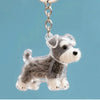 Figurine en plastique transparent d'un chien duveteux suspendue à un anneau de clé en argent.