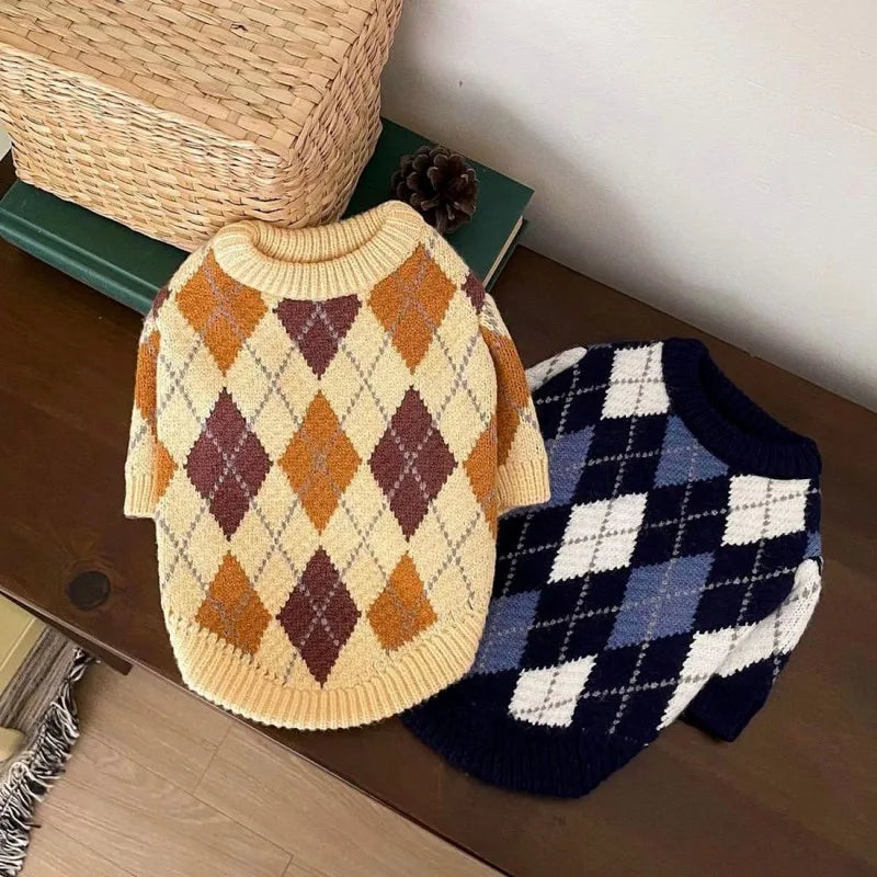 A knitted plaid sweater for dogs featuring shades of orange, brown, and cream.