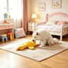 A white fluffy dog is sitting on a rug in front of a pink wooden bed and bedside table.