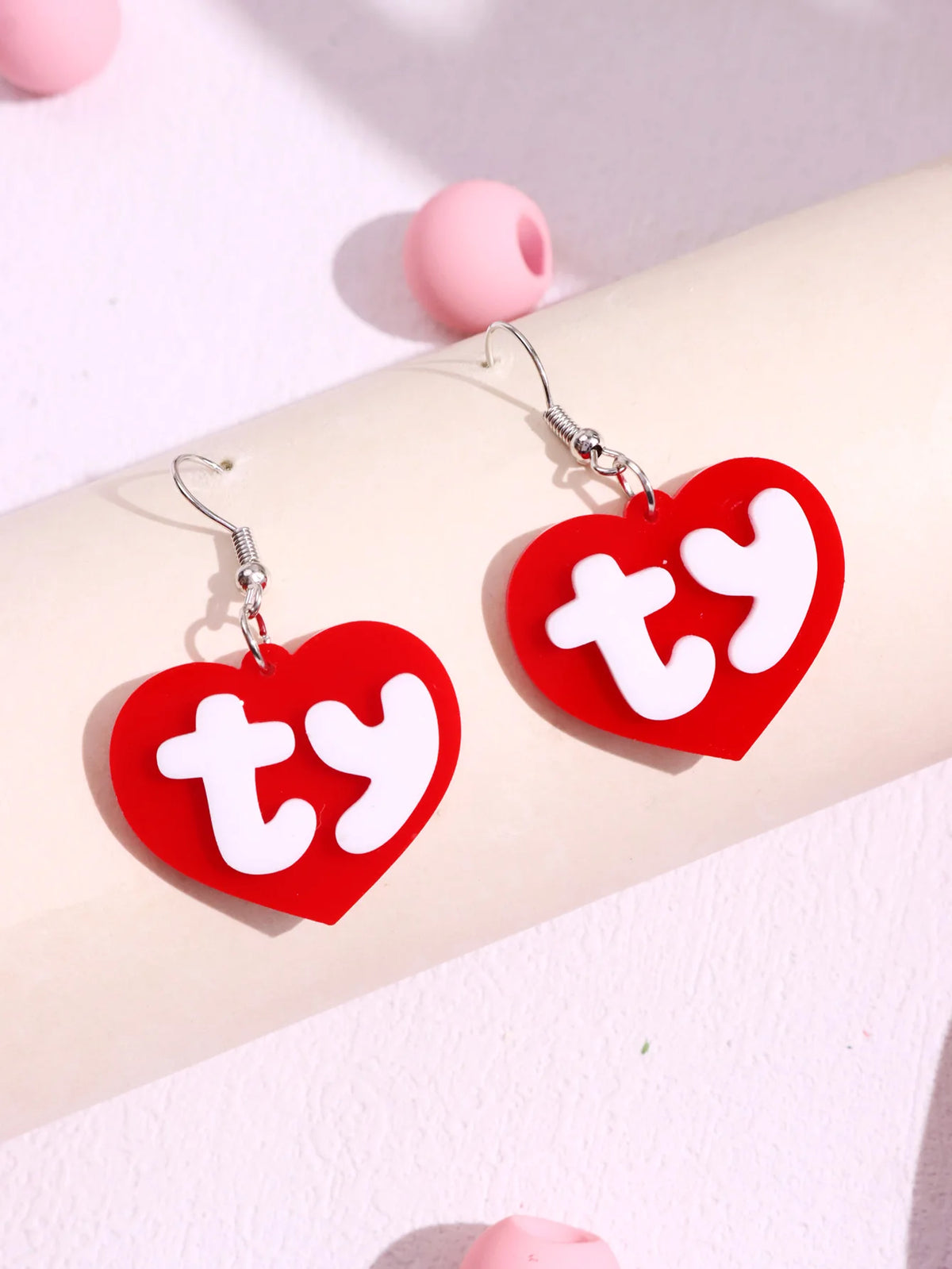 Pair of red acrylic heart stud earrings with white text TY