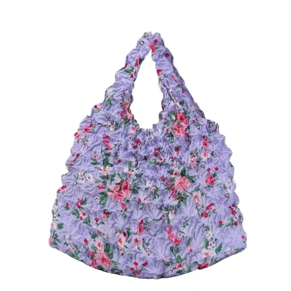 A purple floral fabric tote bag with a gathered top and ruffled edges.