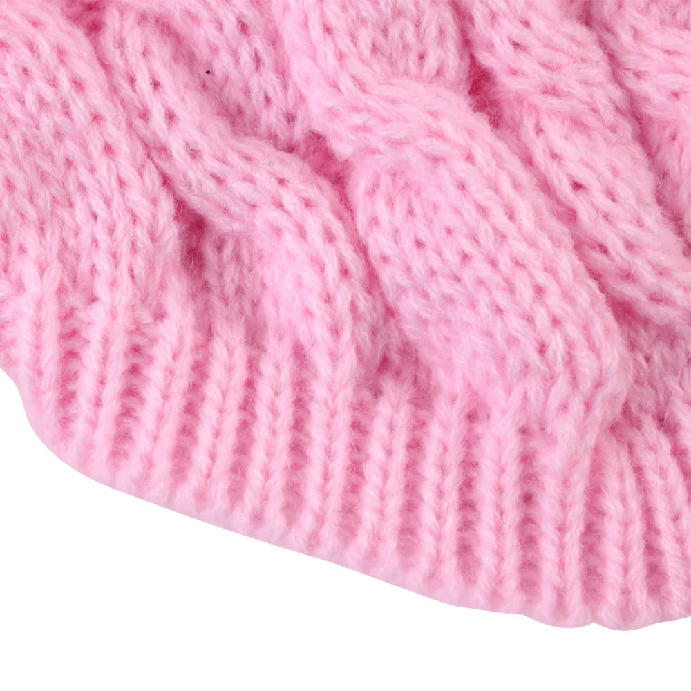 Gros plan d'un pull tricoté rose avec un motif à torsades.