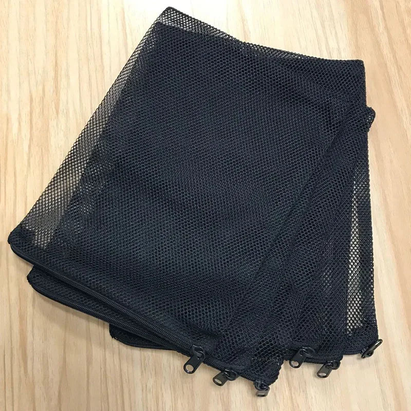 Black mesh bags filled with aquarium filter media resting on a wooden surface.