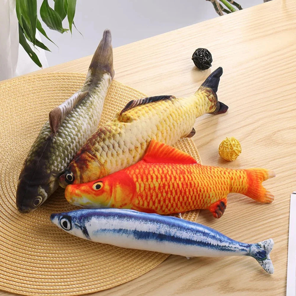 A collection of three fish-shaped plush toys, including a silver, gold, and orange variety, resting on a woven mat.