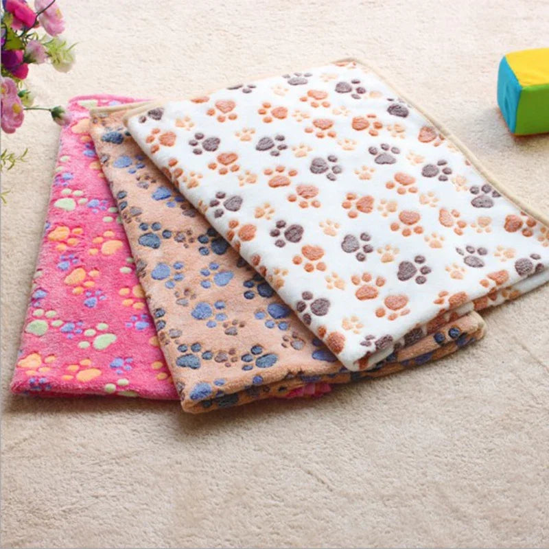 Stack of cozy flannel fleece pet blankets featuring various paw print designs in pink, purple, and white.