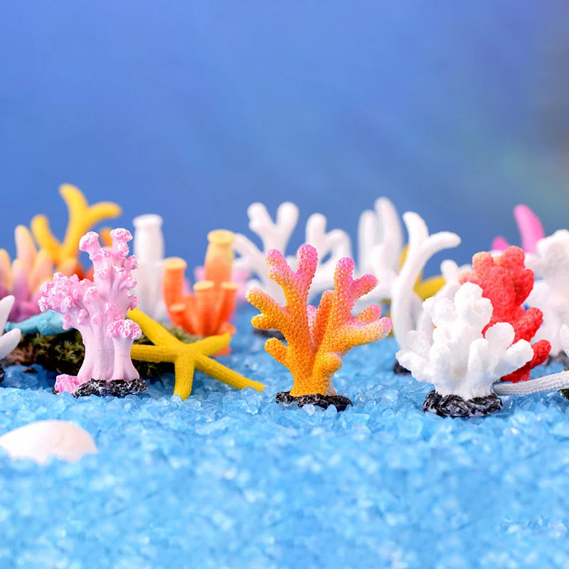 Colorful resin coral aquarium decorations in various pink, orange, and white hues on a blue surface.