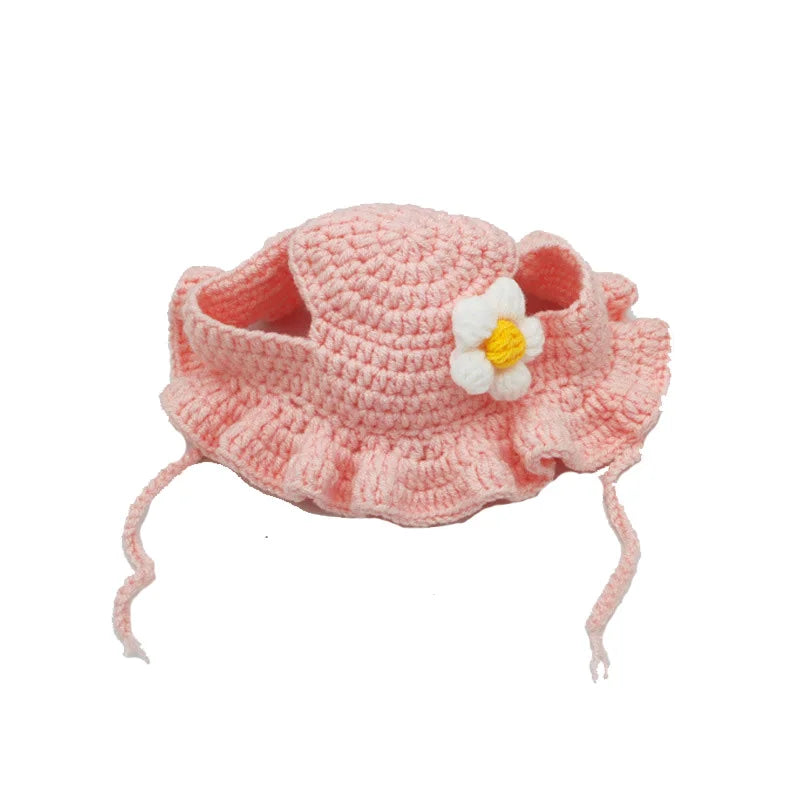 Chapeau pour chat en tricot rose avec fleur blanche et boucles d'oreille pendues.