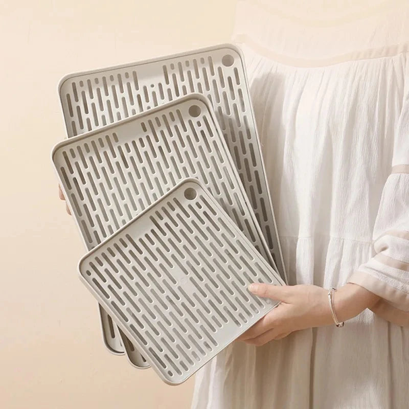 A hand holds a stack of gray universal pet litter boxes for small animals.