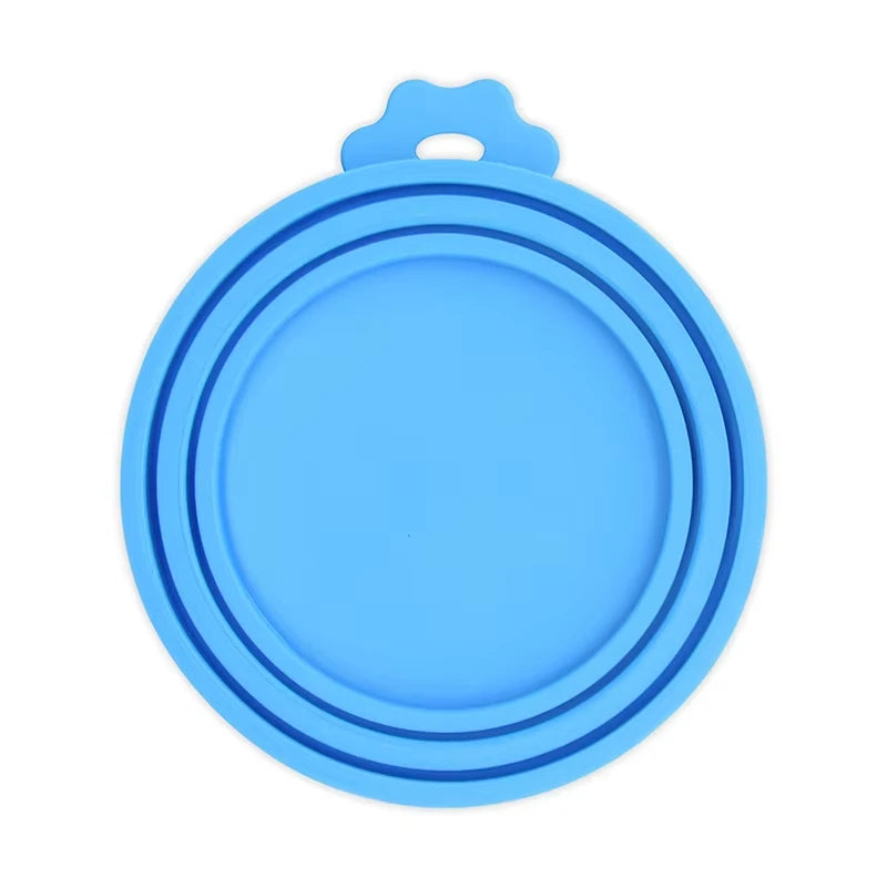A light blue reusable silicone pet food can lid with a spoon attachment.