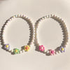 A set of pastel floral beaded necklaces featuring pink, purple, and yellow beads.