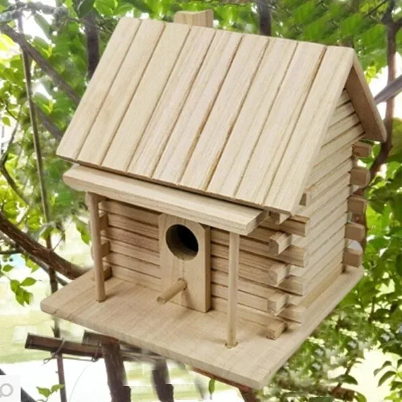 A natural light wood bird nesting box with a slanted roof and an entrance hole, set in a leafy outdoor environment.