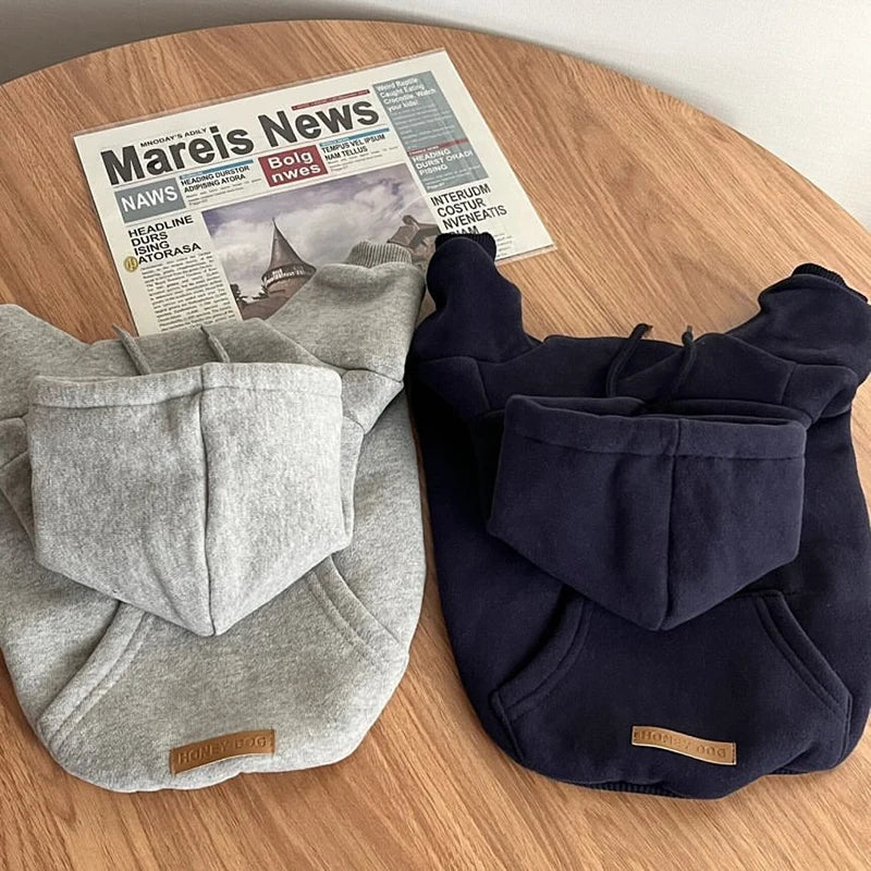 Un ensemble de pulls douillets en polaire bleu marine foncé et gris clair pour chiens, posés sur une surface en bois.