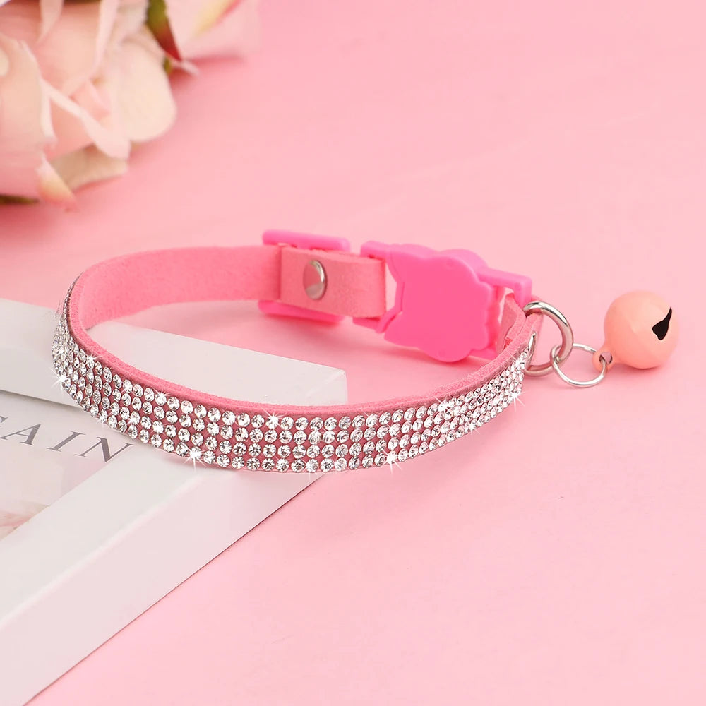 Pink suede rhinestone cat collar with a safety breakaway buckle resting on a white box.