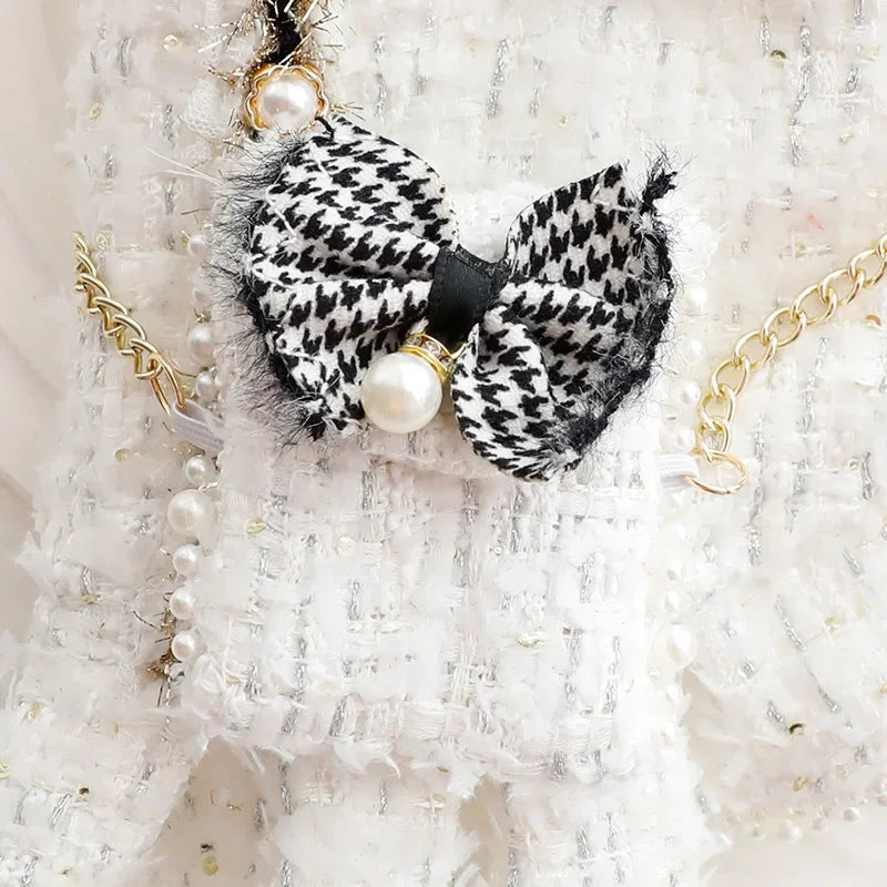 Robe texturée blanche ornée d'un nœud noir et blanc et de bijoux en chaîne dorée.