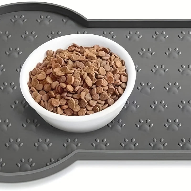 A white silicone dog feeding bowl filled with brown kibble rests on a gray non-slip mat.