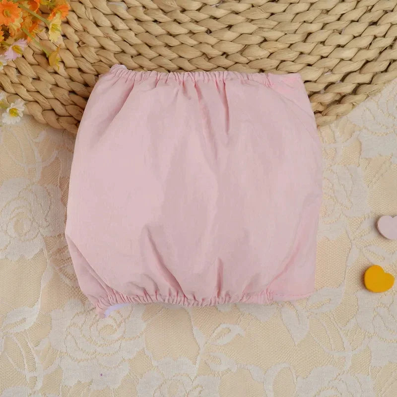Couches pour chiens roses claires réutilisables avec ajustement, montrées sur une surface texturée.