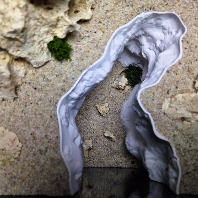 A white 3D rock cave ornament with natural terrain design carved into a light-colored stone surface.