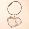 Un charm en verre clair en forme de chat fixé à une breloque à cordon tressé.