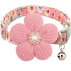 A pink floral dog collar with a textured fabric strap and a silver rhinestone bell.