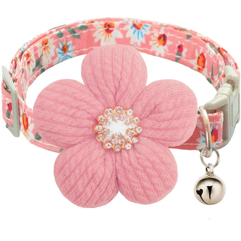 A pink floral dog collar with a textured fabric strap and a silver rhinestone bell.